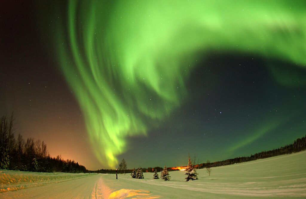 Northern Lights reflecting on a frozen lake in Lapland, Finland – A stunning aurora display over the Arctic winter landscape.