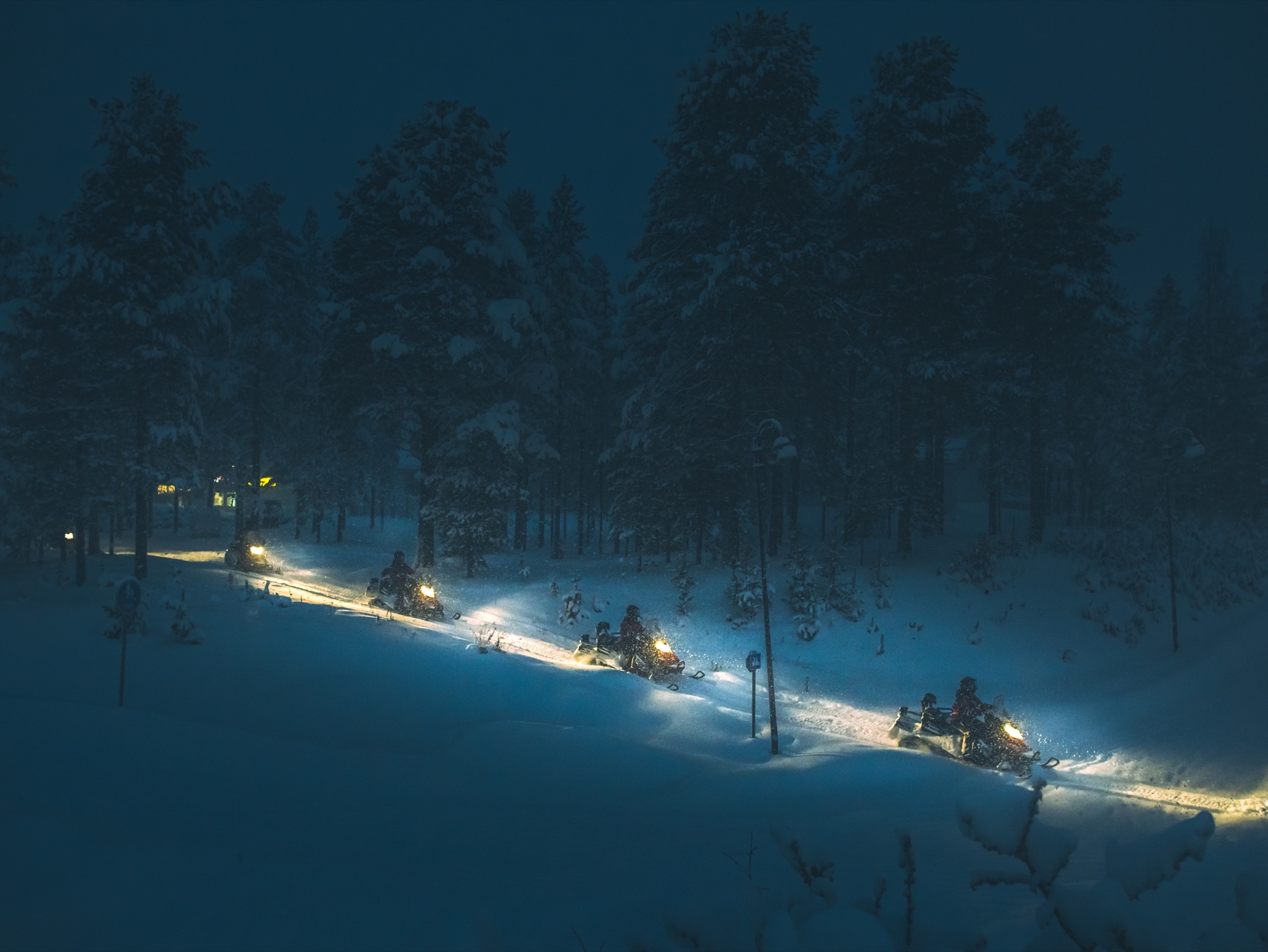 Snowmobile safari through a snowy forest near Levi