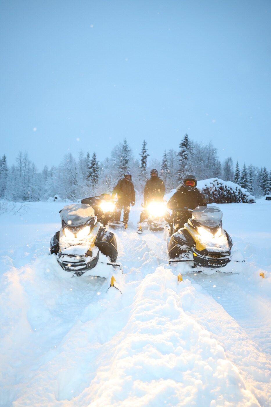 Snowmobiles and riders surrounded by fresh snow in Levi